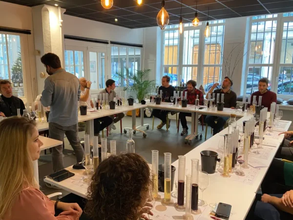 Personnes assistant à un atelier d'assemblage de vin dans un chai urbain à Lyon avec Atripik.